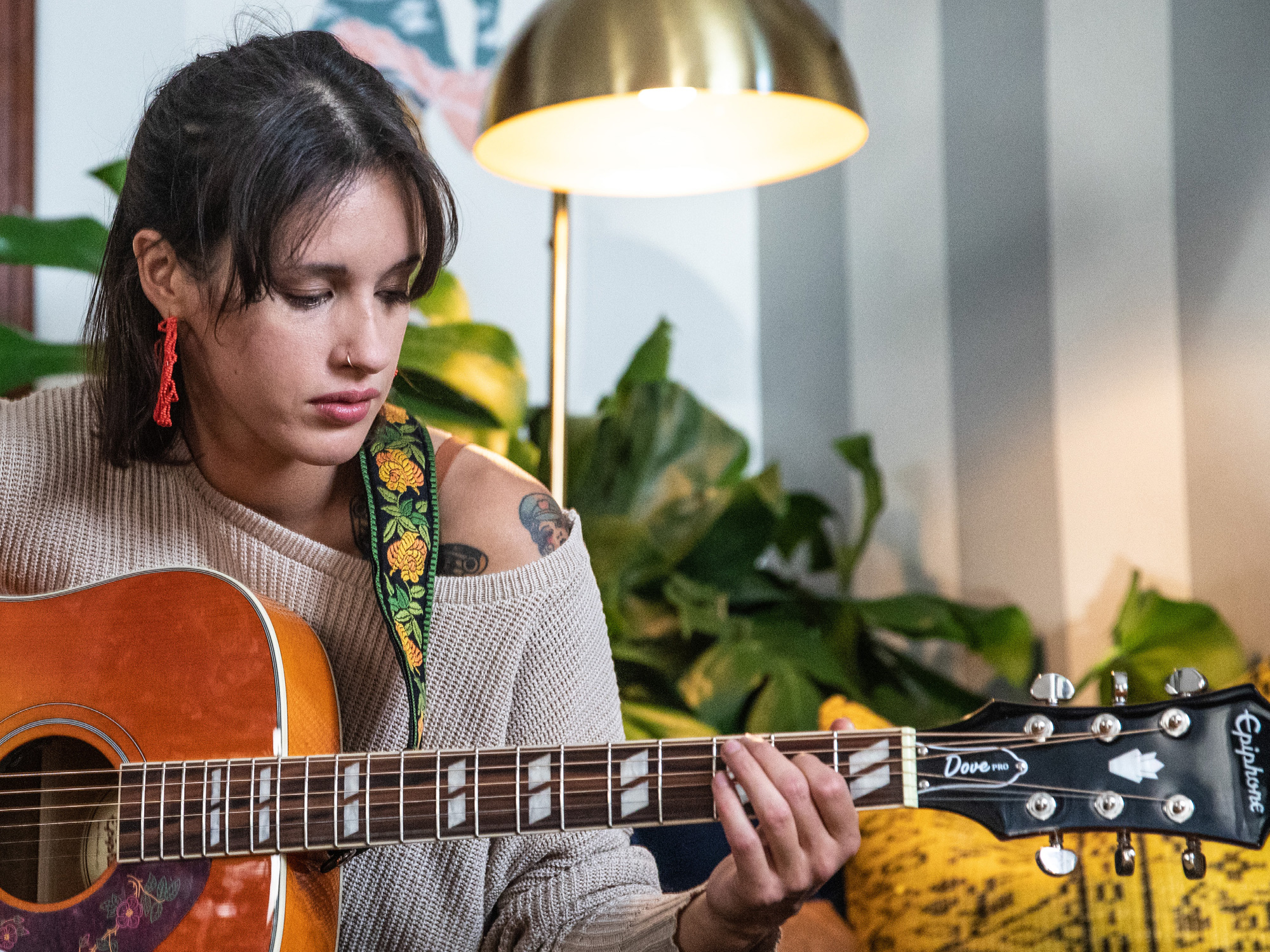 Lifestyle photograph of a musician playing acoustic guitar at home